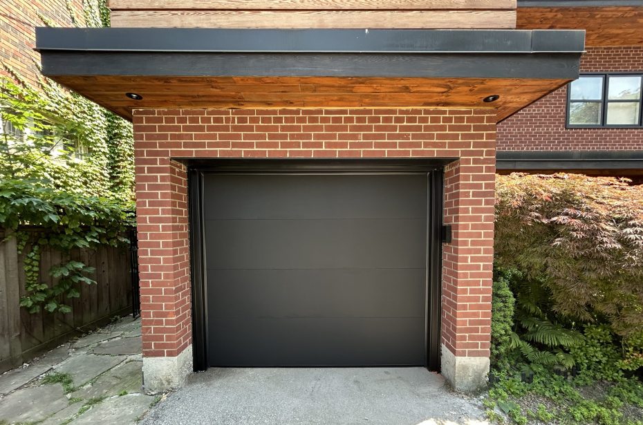Mid-range view of a black flush insulated steel garage door with clean aluminum capping.