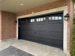 Angle view of a newly installed black recessed long panel garage door on a brick home in Caledon East