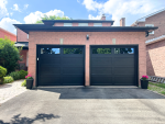 Straight-on full front view of two black recessed long panel insulated garage doors installed on a red brick home in Richmond Hill.