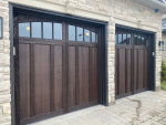 Side angle view of installed dark wood-grain garage doors with arched glass windows in Woodbridge, Ontario.