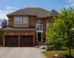 Front view of a Whitby home featuring two dark oak insulated steel coach garage doors with Madison windows.