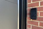 Close-up of a newly installed garage door keypad alongside a premium black insulated steel garage door panel.