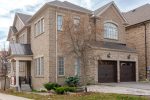 Full exterior view of a Richmond Hill brick house featuring a double garage equipped with matching walnut-finish coach house doors.