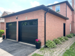 Right-side angle view highlighting the black aluminum capping and sleek black finish of newly installed long panel garage doors on a Richmond Hill home.