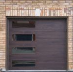 Close-up of a modern plank-style garage door in a dark walnut woodgrain finish with four frosted vertical side windows.