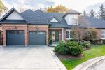 Full front view of a brick home showcasing two iron ore long panel recessed garage doors installed by Dodds.