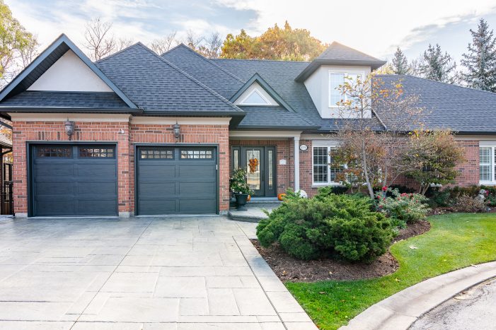 Full front view of a brick home showcasing two iron ore long panel recessed garage doors installed by Dodds.